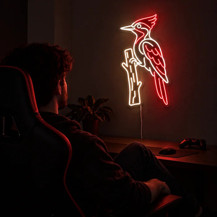 Roter Specht Neon LED Schild über dem Gaming-Schreibtisch, davor ein Spieler im Gaming-Stuhl