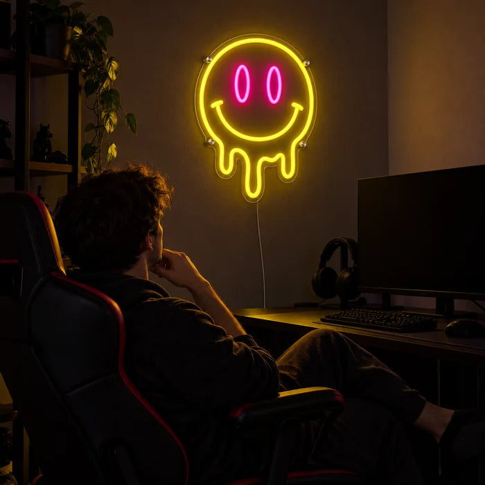 Schmelzender Smiley Neon LED Schild über dem Gaming-Schreibtisch, davor ein Spieler im Gaming-Stuhl