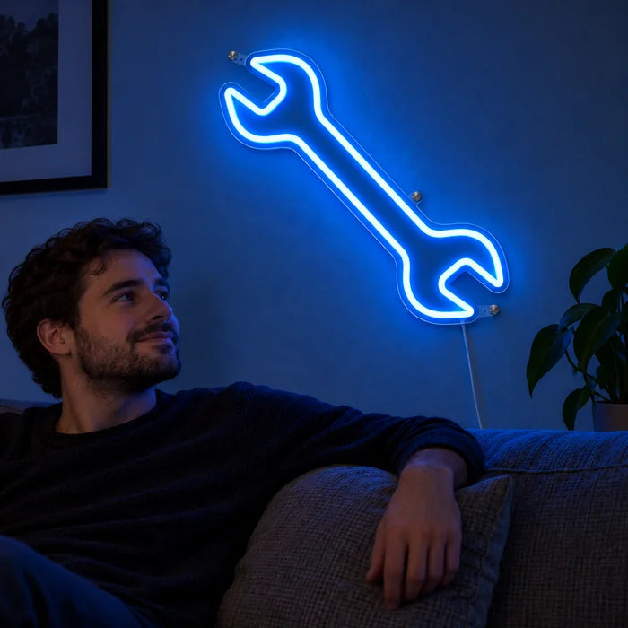 Schraubenschlüssel Neon LED Schild an der Wohnzimmerwand, davor entspannt eine Person auf dem Sofa