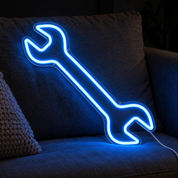 Schraubenschlüssel Neon LED Schild auf einem gemütlichen Sofa zwischen Kissen und Decke