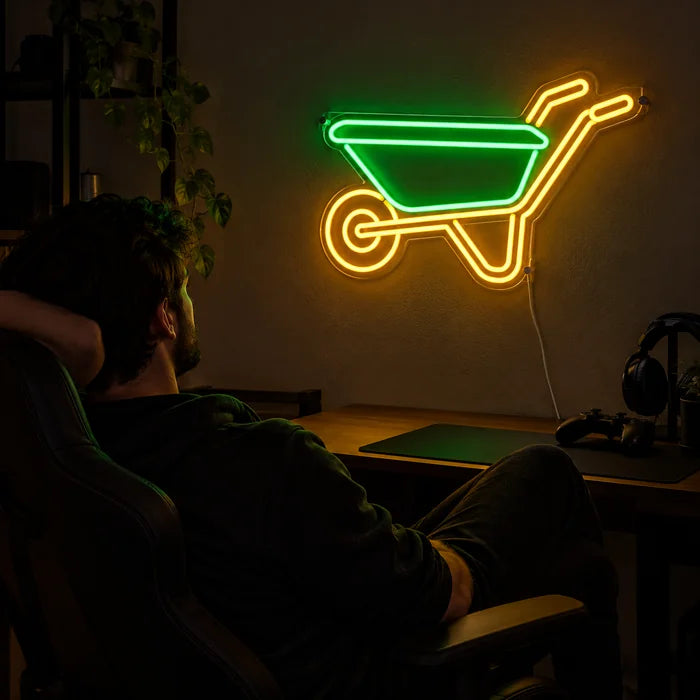 Schubkarre Neon LED Schild über dem Gaming-Schreibtisch, davor ein Spieler im Gaming-Stuhl