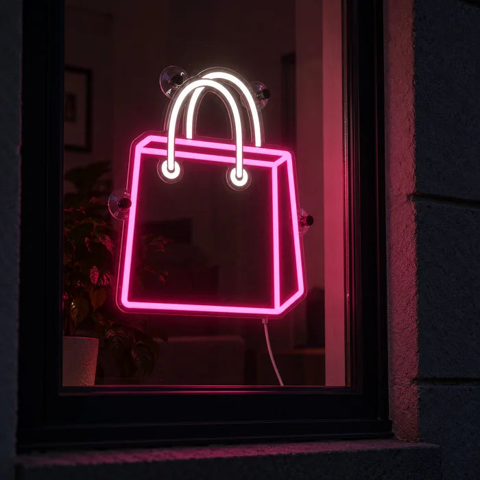 Shoppingtasche Neon LED Schild im Fenster, von der nächtlichen Straße aus gesehen