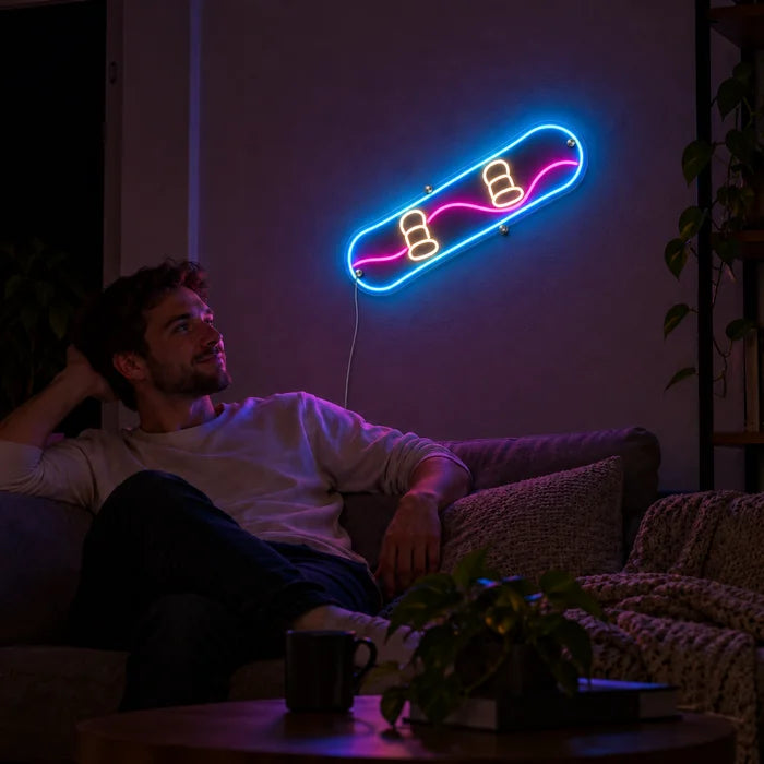 Snowboard Neon LED Schild an der Wohnzimmerwand, davor entspannt eine Person auf dem Sofa