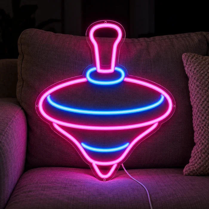 Spielkreisel Neon LED Schild auf einem gemütlichen Sofa zwischen Kissen und Decke