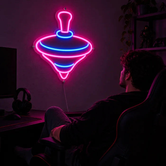 Spielkreisel Neon LED Schild über dem Gaming-Schreibtisch, davor ein Spieler im Gaming-Stuhl