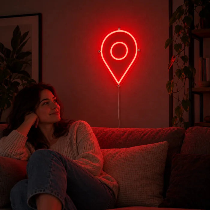 Standortmarker Neon LED Schild an der Wohnzimmerwand, davor entspannt eine Person auf dem Sofa