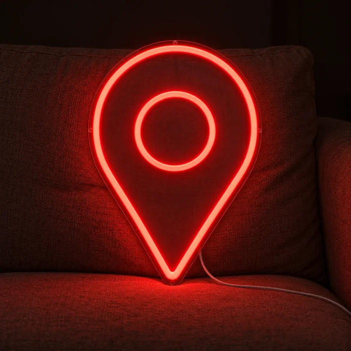 Standortmarker Neon LED Schild auf einem gemütlichen Sofa zwischen Kissen und Decke
