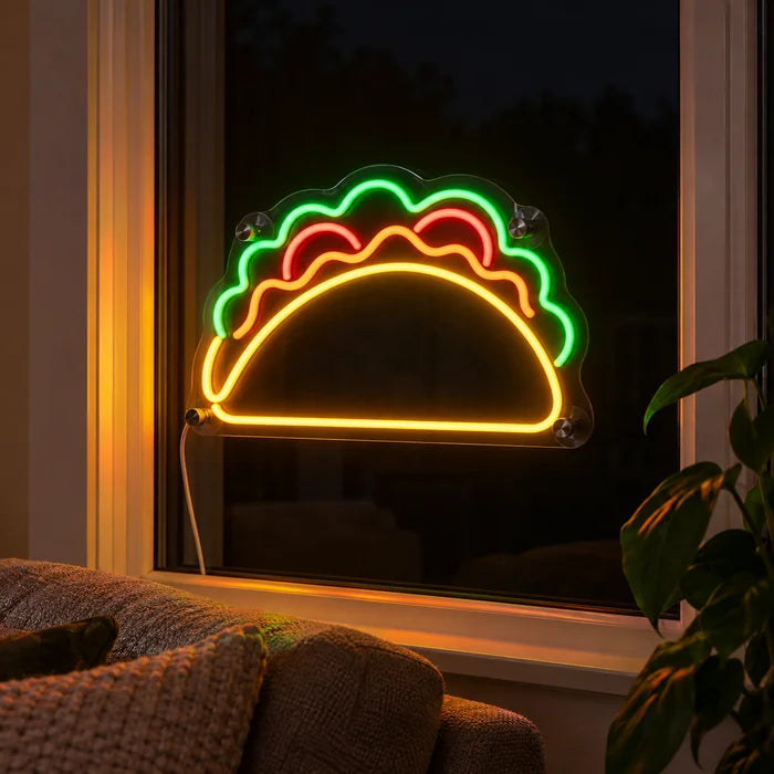 Taco-Zeit Neon LED Schild abends im Fenster eines gemütlichen Wohnzimmers
