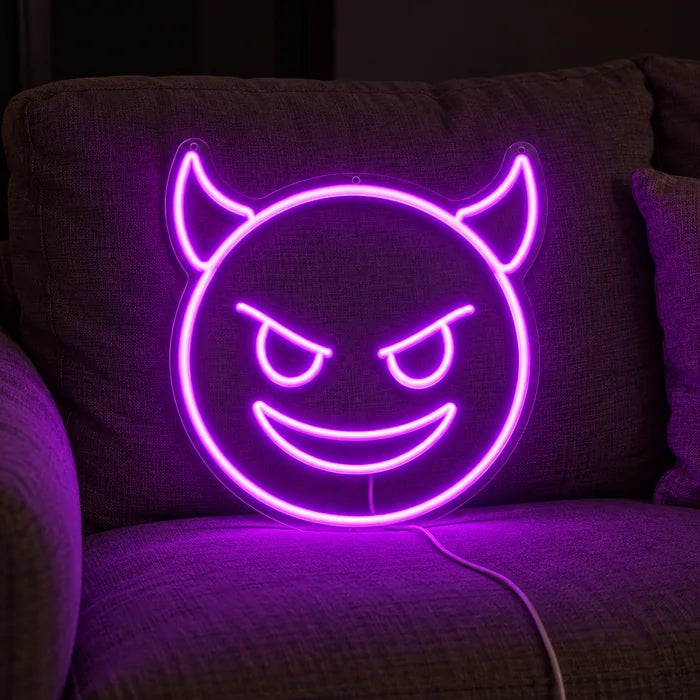 Teufelsgrinsen Neon LED Schild auf einem gemütlichen Sofa zwischen Kissen und Decke