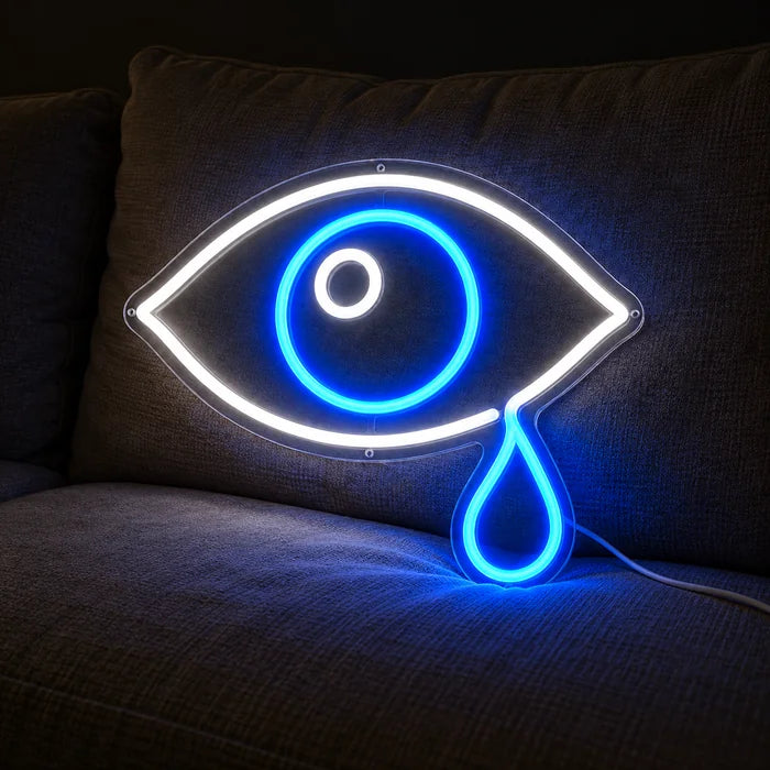 Tränenauge Neon LED Schild auf einem gemütlichen Sofa zwischen Kissen und Decke