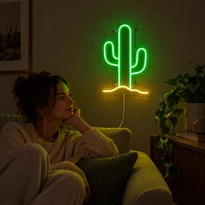 Wüstenkaktus Neon LED Schild an der Wohnzimmerwand, davor entspannt eine Person auf dem Sofa