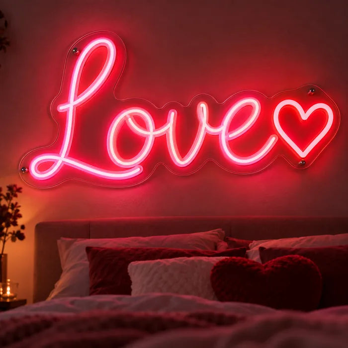 Neon LED Schild mit Schriftzug „Love“ und Herz in Pink und Rot über dem Bett