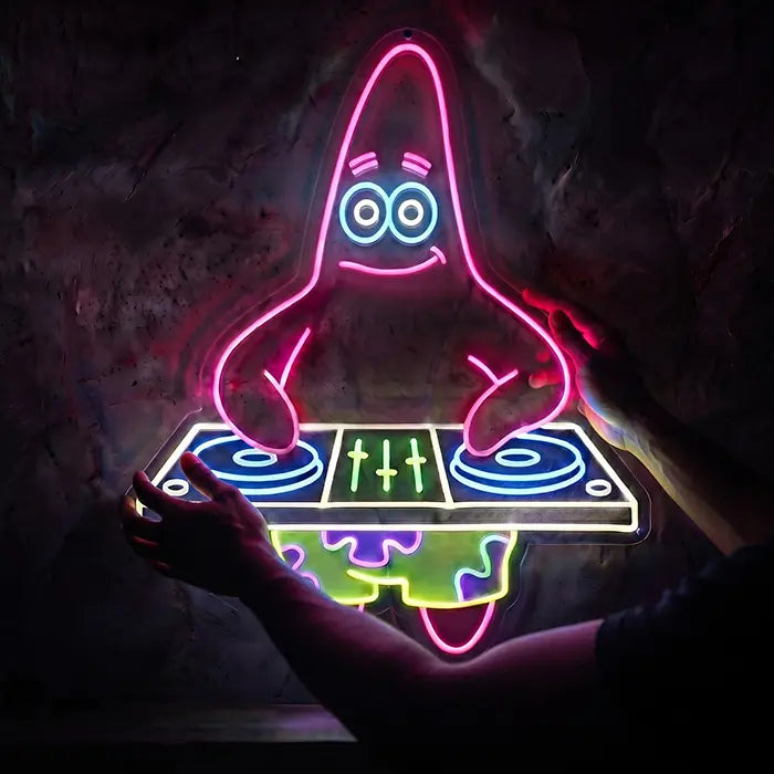 Patrick DJ Neon LED Schild wird mit beiden Händen vor eine Steinwand gehalten, Nahaufnahme des DJ-Motivs