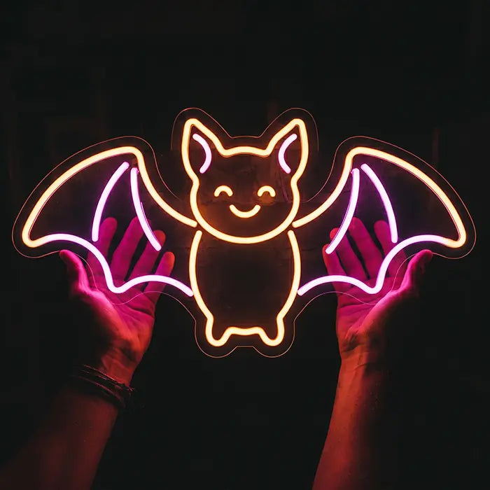 Fledermaus Neon LED Schild liegt auf zwei Handflächen vor schwarzem Hintergrund im Größenvergleich