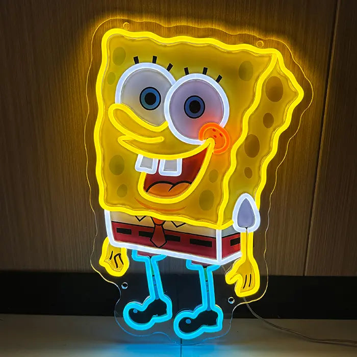 Schwammfigur Neon LED Schild leuchtend an einer Holzwand, gelbe Kontur, blaue Beine und breites Grinsen