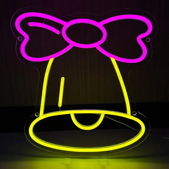 Glöckchen Neon LED Schild frontal vor dunklem Hintergrund, gelbe Glocke mit rosa Schleife darüber
