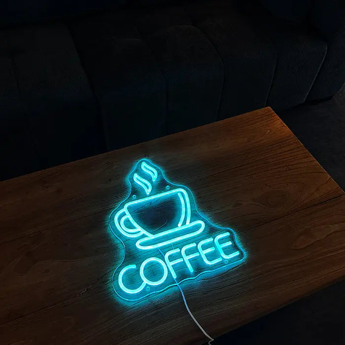 Coffee Tasse Neon LED Schild liegend auf einem Holztisch, Tasse und Schriftzug leuchten eisblau
