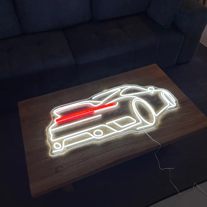 GT-Sportwagen Neon LED Schild liegend auf einem Holztisch vor einem Sofa, weiß und rot leuchtend