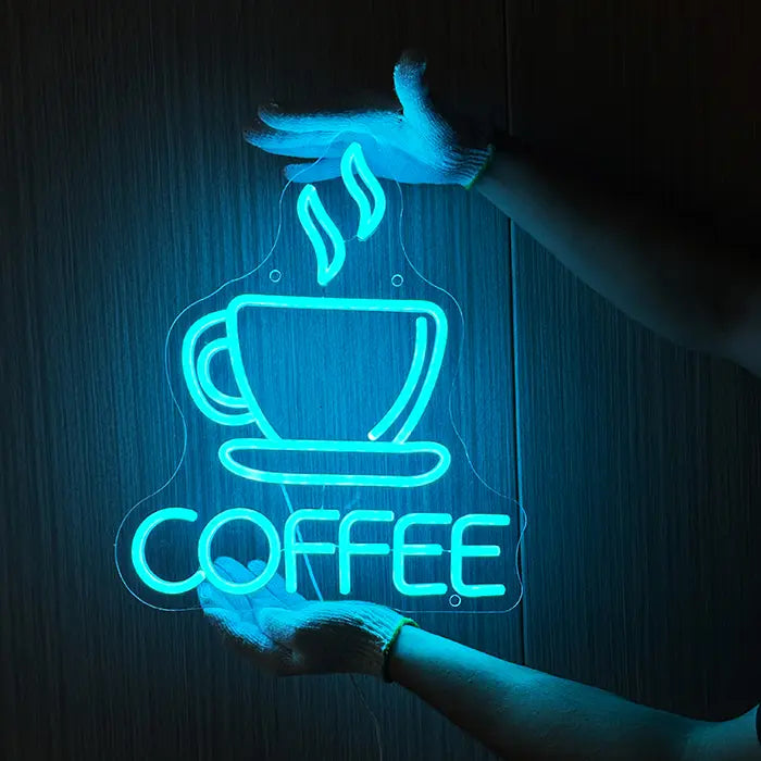Coffee Tasse Neon LED Schild wird mit Handschuhen an eine dunkle Holzwand gehalten