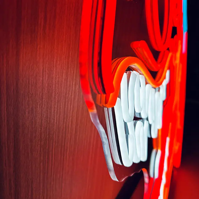 T-Rex Dino Neon LED Schild seitlich an der Wand fotografiert, Zähne und Acrylkante aus der Nähe