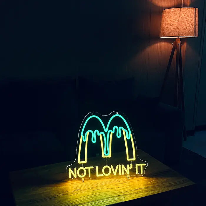 McDonald's Not Lovin' It Neon LED Schild auf einem Holztisch im dunklen Wohnzimmer, daneben eine Stehlampe