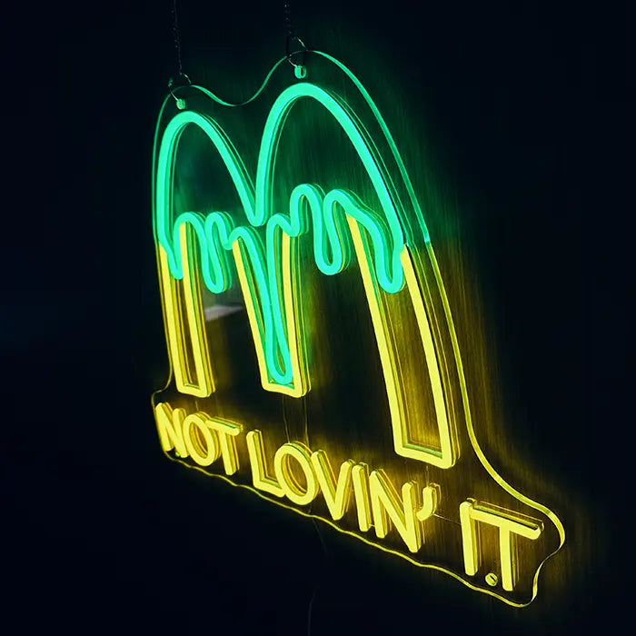 McDonald's Not Lovin' It Neon LED Schild an Ketten aufgehängt, gelb und grün leuchtend vor dunkler Wand