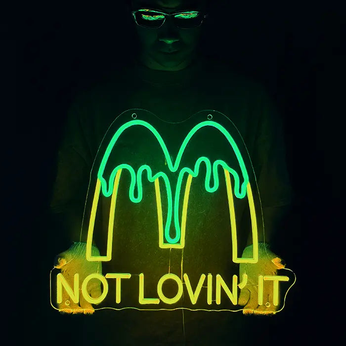 McDonald's Not Lovin' It Neon LED Schild wird mit Handschuhen vor den Körper gehalten