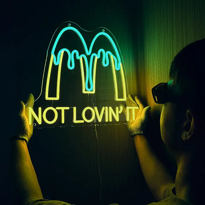 McDonald's Not Lovin' It Neon LED Schild wird an der Wand ausgerichtet, eine Person mit Handschuhen hält es fest