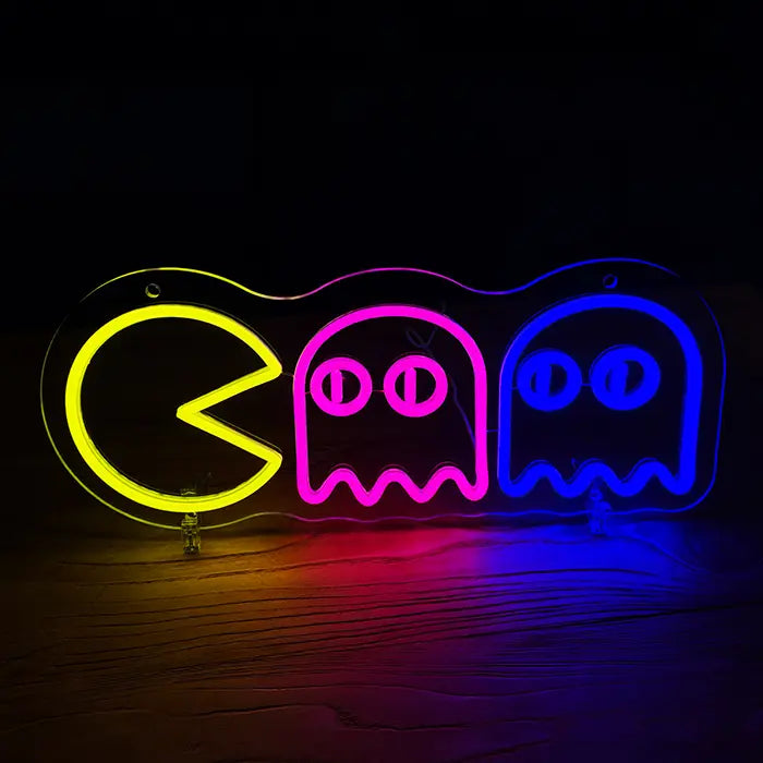 Retro Ghosts Neon LED Schild frontal an dunkler Wand, gelbe Arcade-Figur jagt einen pinken und einen blauen Geist
