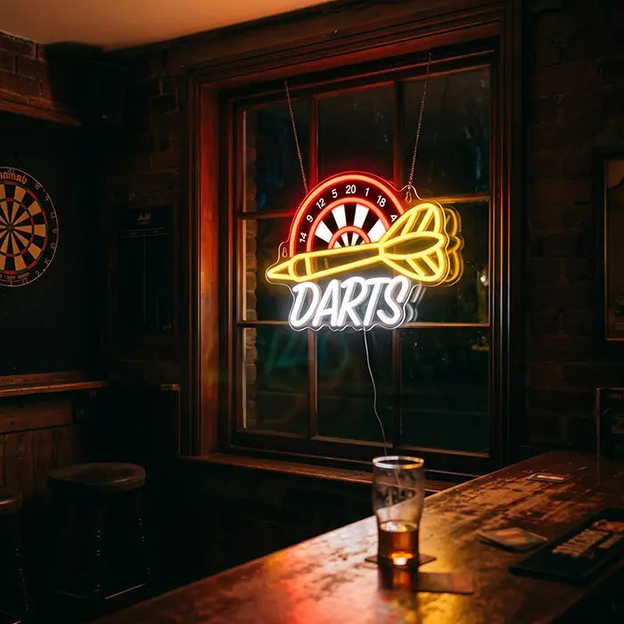 Darts Neon LED Schild mit UV-Druck im Fenster eines Pubs, davor ein Tisch mit Bierglas, an der Wand eine Dartscheibe
