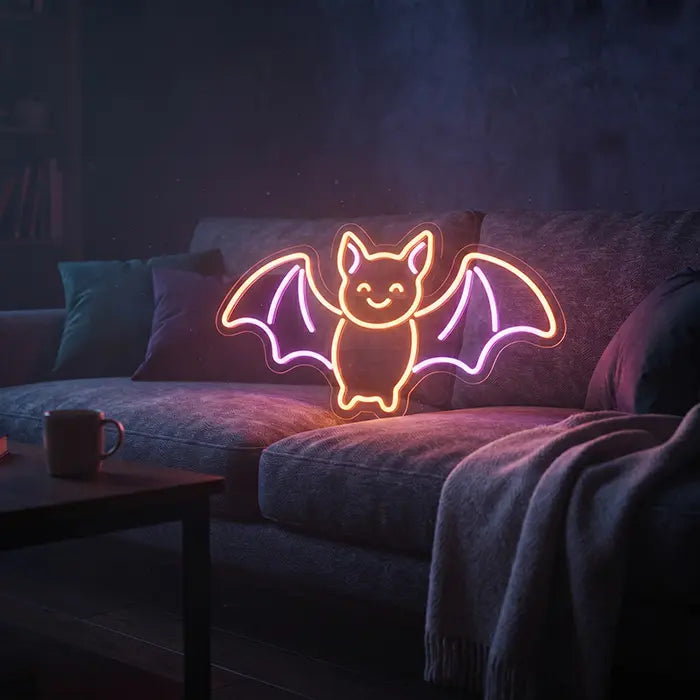 Fledermaus Neon LED Schild auf einem grauen Sofa mit Kissen und Decke im abgedunkelten Wohnzimmer
