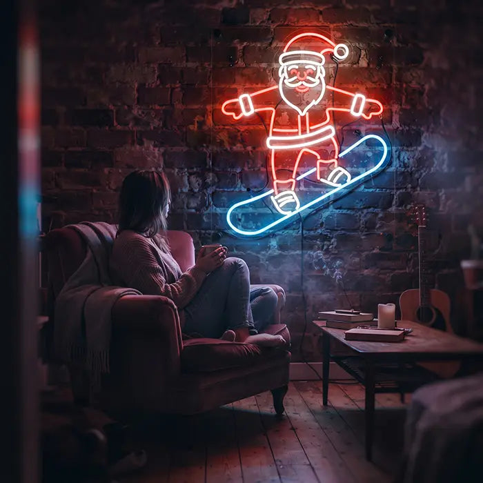 Weihnachtsmann mit Snowboard Neon LED Schild an der Wand über einer Frau im Sessel mit Tasse, daneben ein Couchtisch