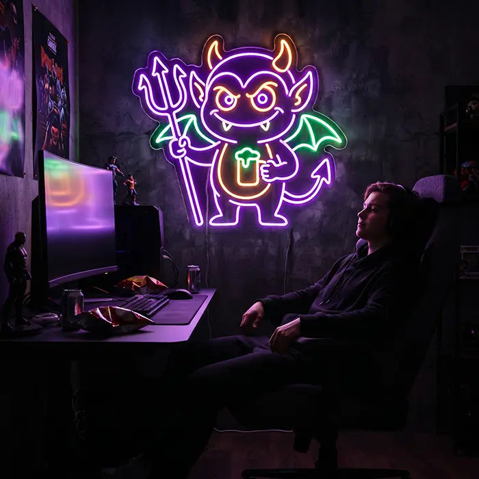 Teufel Neon LED Schild über dem Gaming-Setup, ein Gamer sitzt entspannt im Stuhl davor am Schreibtisch