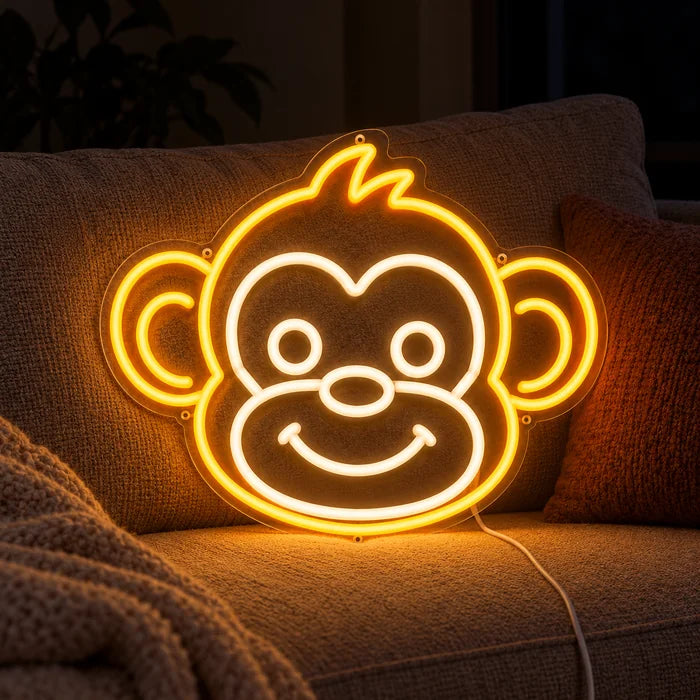 Affengesicht Neon LED Schild auf einem gemütlichen Sofa zwischen Kissen und Decke