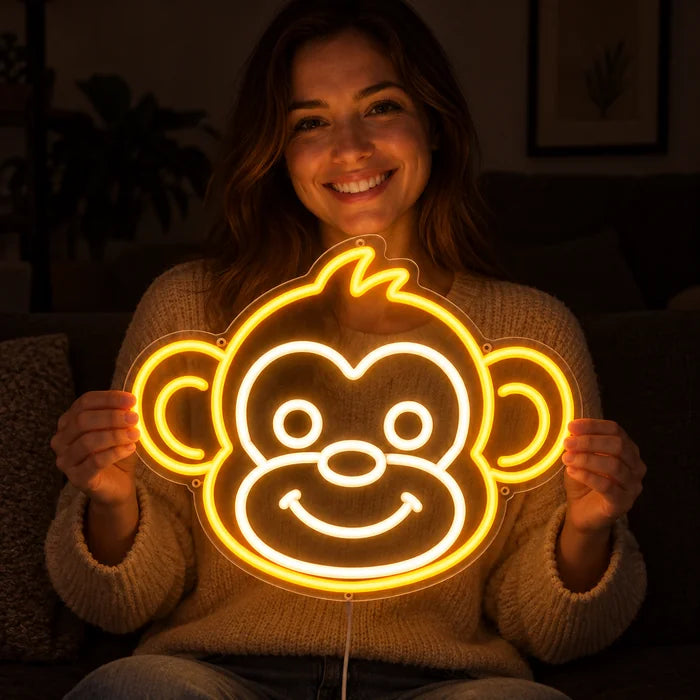 Affengesicht Neon LED Schild in den Händen einer lächelnden Frau vor dunklem Hintergrund