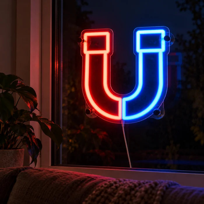 Anziehungskraft Neon LED Schild abends im Fenster eines gemütlichen Wohnzimmers