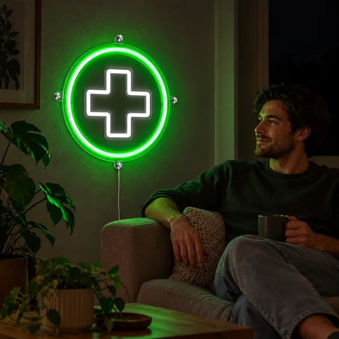 Apothekenkreuz Neon LED Schild an der Wohnzimmerwand, davor entspannt eine Person auf dem Sofa