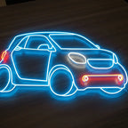 Detailaufnahme eines LED-Neon-Schildes in Form eines Smart Car, das auf einem dunklen Holztisch steht.