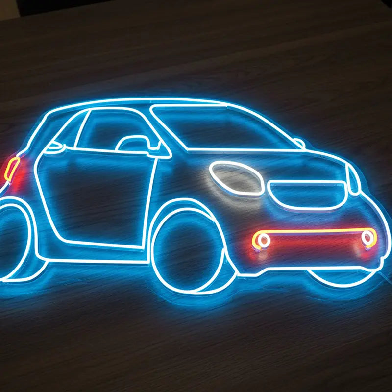 Detailaufnahme eines LED-Neon-Schildes in Form eines Smart Car, das auf einem dunklen Holztisch steht.
