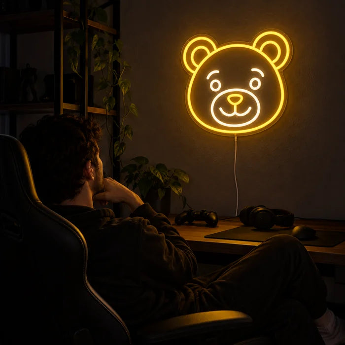 Bärenlächeln Neon LED Schild über dem Gaming-Schreibtisch, davor ein Spieler im Gaming-Stuhl