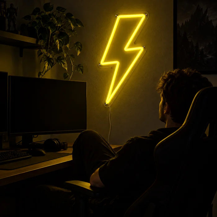 Blitz Neon LED Schild über dem Gaming-Schreibtisch, davor ein Spieler im Gaming-Stuhl