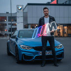 Ansicht des BMW M Power LED-Neonschildes bei Nacht, das eine dezente, aber farbintensive Beleuchtung in einem Raum schafft