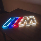 Stylisches LED-Neonschild des BMW M Logos, das eine Wand in Blau, Rot und Weiß beleuchtet, perfekt für eine Garage oder ein Gaming-Zimmer