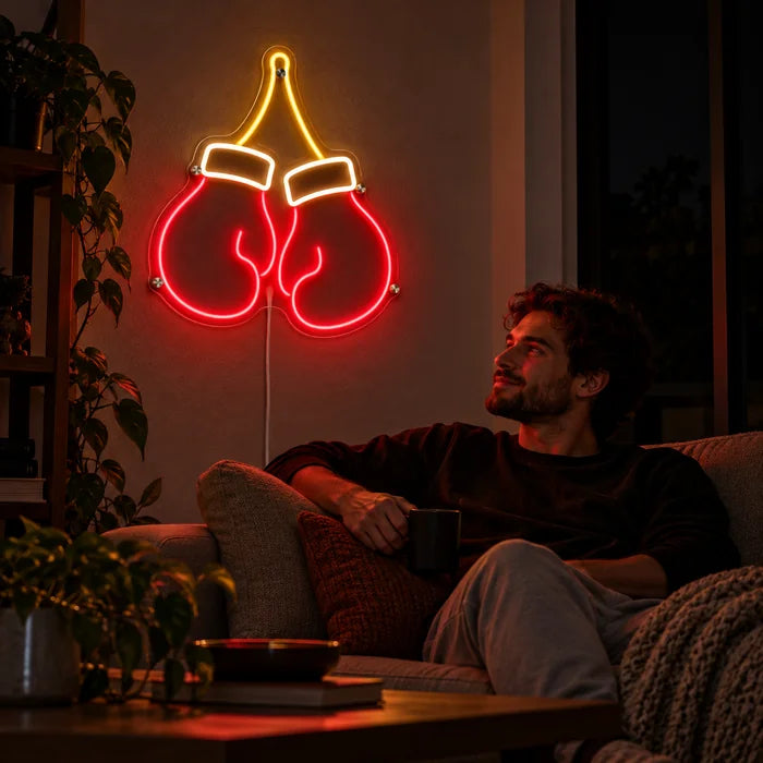 Boxhandschuhe Neon LED Schild an der Wohnzimmerwand, davor entspannt eine Person auf dem Sofa
