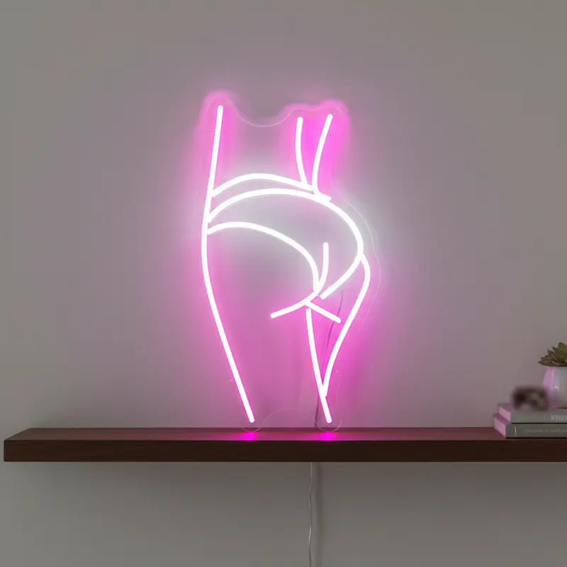 Moderne Kunst-Deko: Ein Neon-Motiv einer weiblichen Figur in Pink und Weiß vor einer grauen Betonwand.

