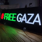 Statement-Neon-Sign: FREE GAZA Schriftzug in Grün und Weiß mit einem roten Hashtag vorne.