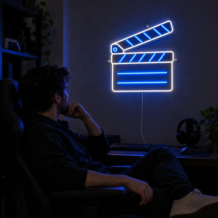 Filmklappe Neon LED Schild über dem Gaming-Schreibtisch, davor ein Spieler im Gaming-Stuhl