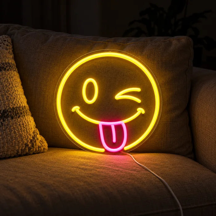 Frecher Smiley Neon LED Schild auf einem gemütlichen Sofa zwischen Kissen und Decke