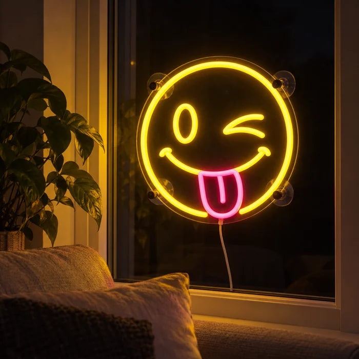 Frecher Smiley Neon LED Schild abends im Fenster eines gemütlichen Wohnzimmers