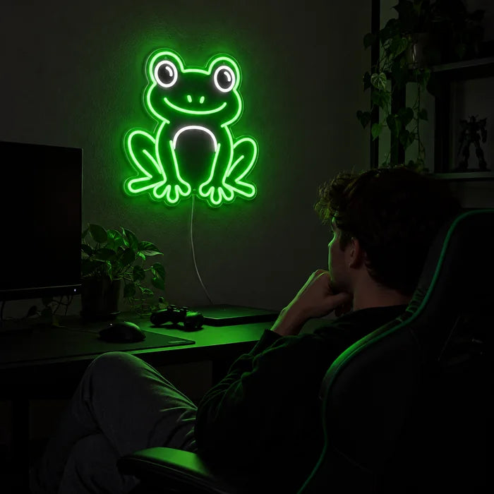 Froschfreund Neon LED Schild über dem Gaming-Schreibtisch, davor ein Spieler im Gaming-Stuhl